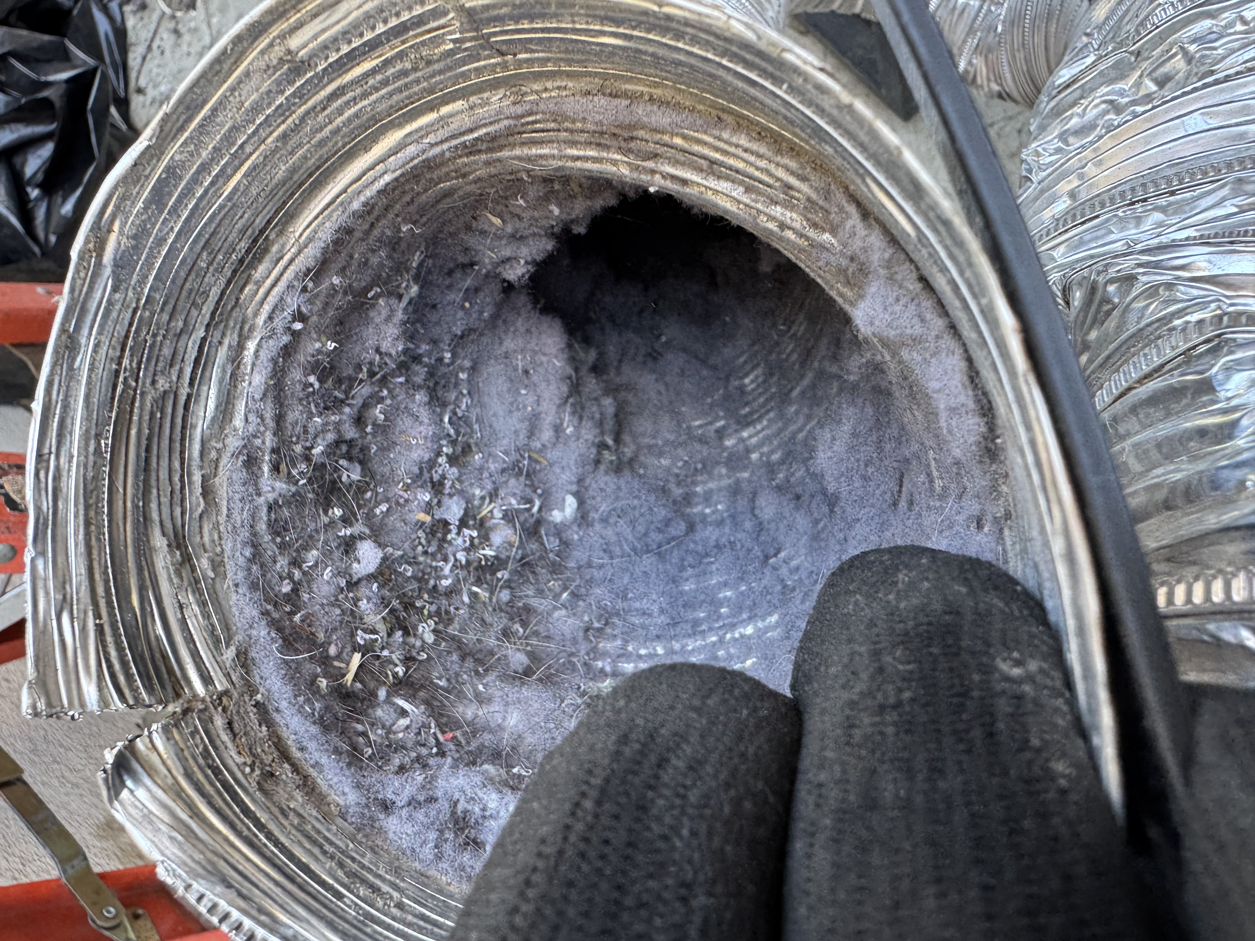 Interior of a dirty duct clogged with lint and debris being cleaned
